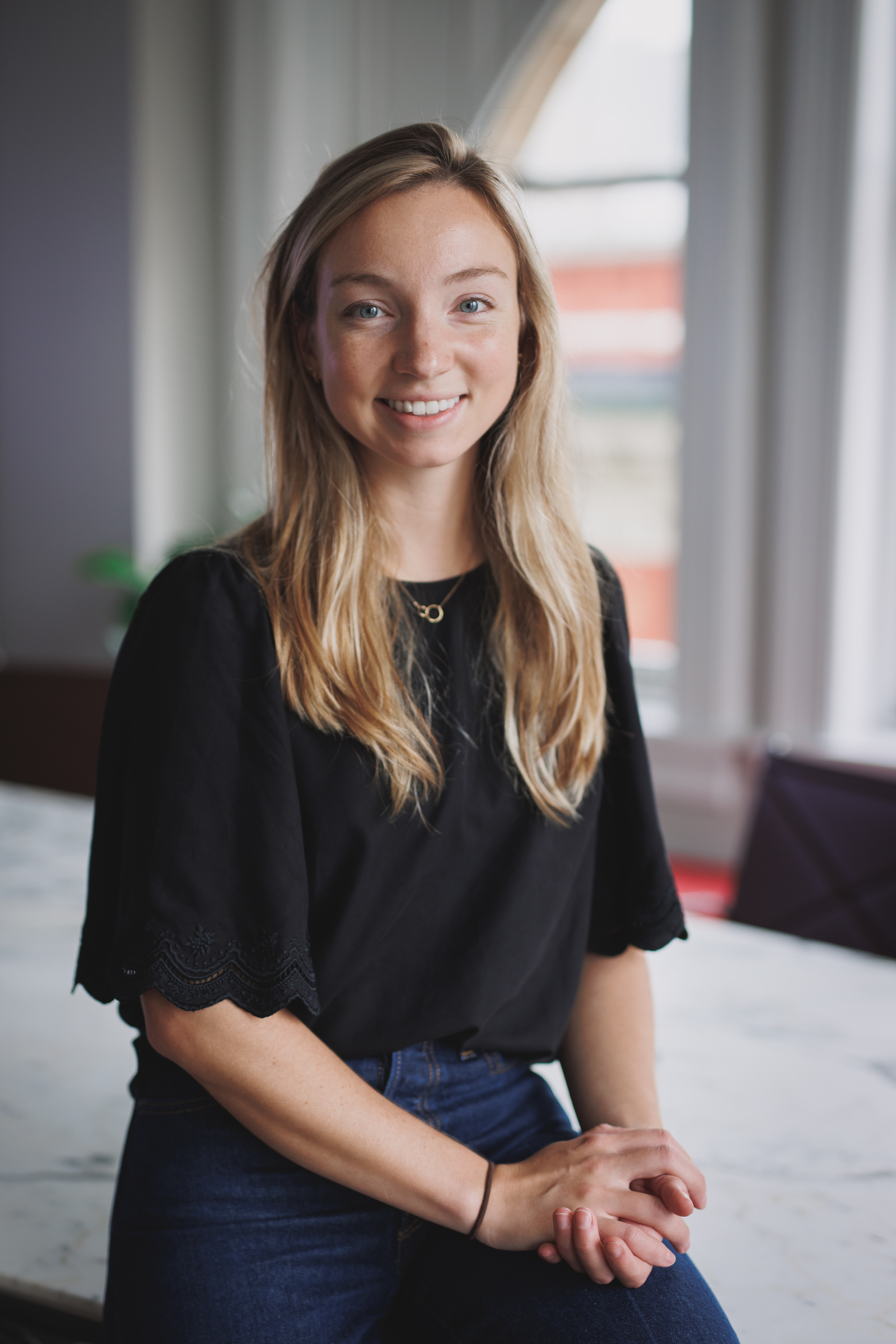 Executive Portrait: young businesswoman smiling, leaning against the table of a conference room